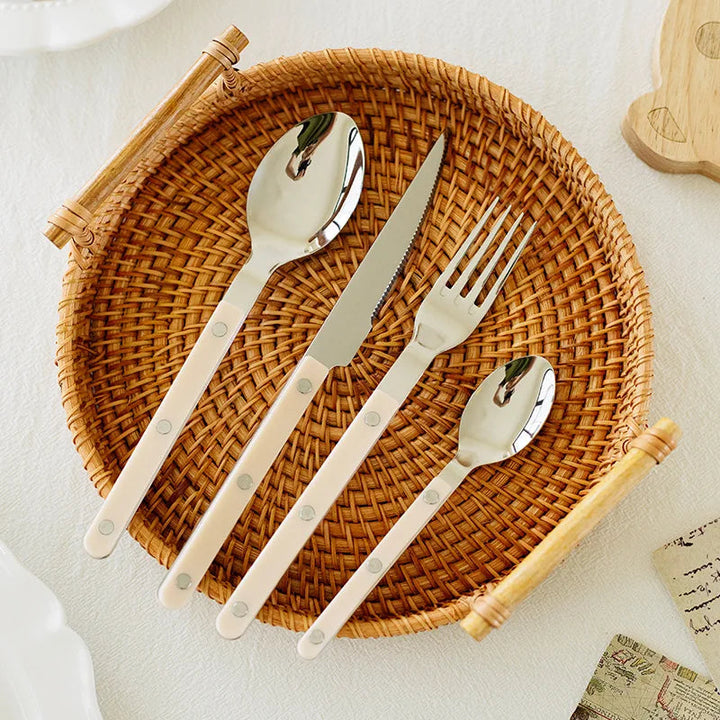 Close-up of a 24-piece stainless steel flatware set, featuring knives, forks, and spoons.
