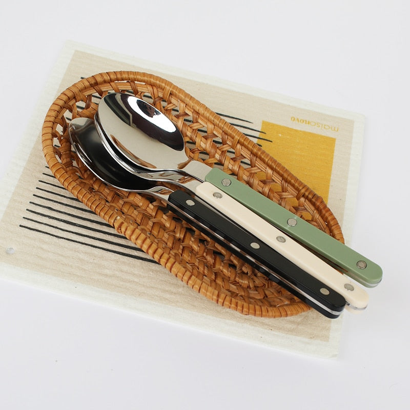 Shiny 24-piece stainless steel flatware set on a dining table, ready for a meal.