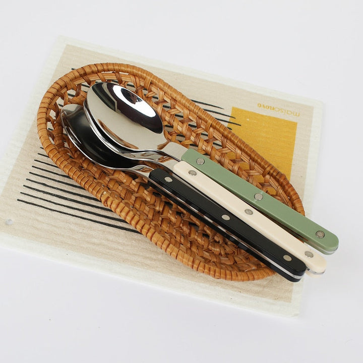 Shiny 24-piece stainless steel flatware set on a dining table, ready for a meal.