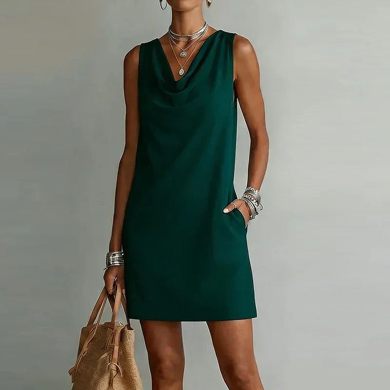 Women's cowl neck mini dress with practical pockets, ideal for casual summer wear. Sleeveless A-line design.