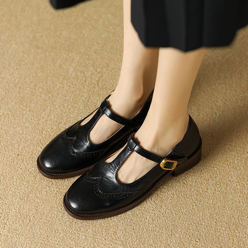 Detailed shot of the brogue accents on the toe of a women's black T-Bar Mary Jane shoe.