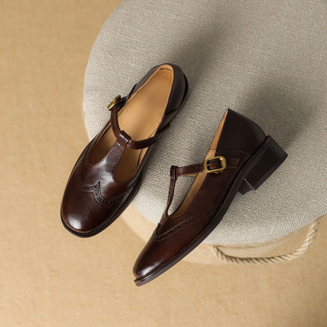 Side view of a woman's black T-Bar Mary Jane shoe, showcasing brogue and block heel design.