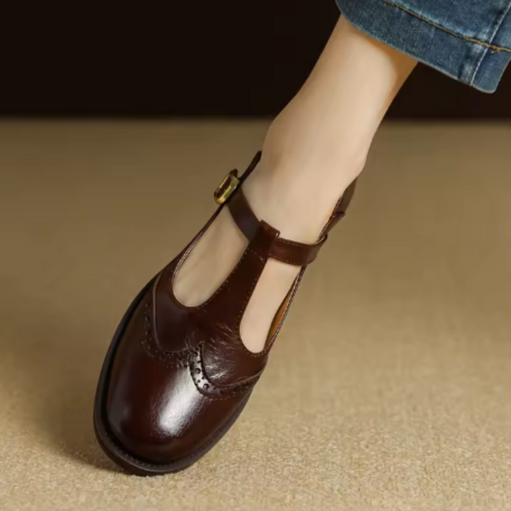 Pair of beige women's T-Bar Mary Janes with brogue details, perfect for vintage style outfits.