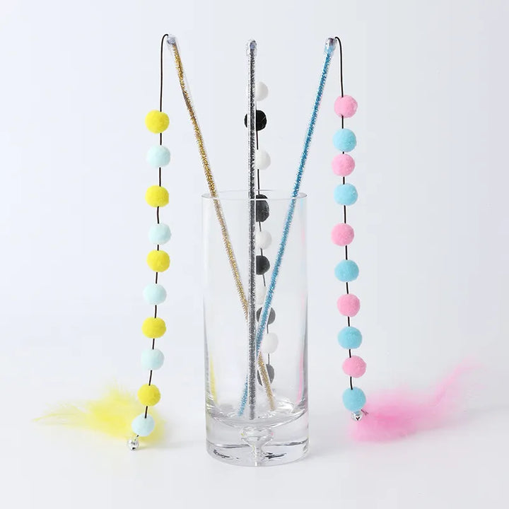Vibrant interactive cat toy with natural feathers and fluffy pom poms on a flexible rod.