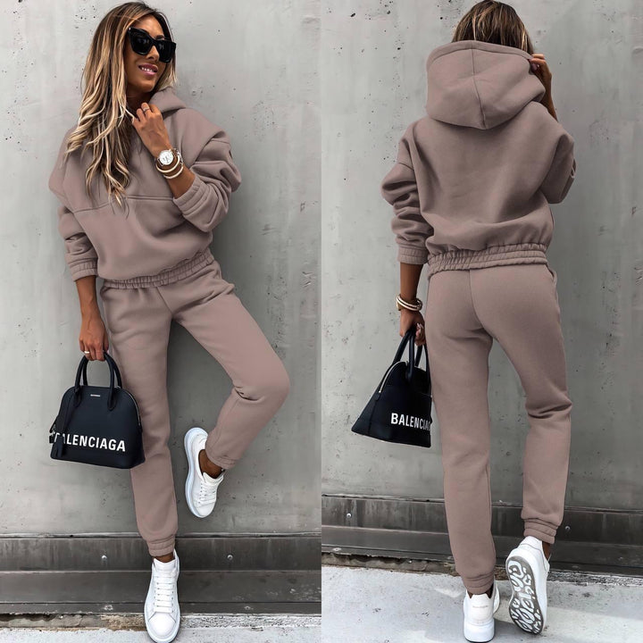 Woman relaxing comfortably on sofa in a cozy, chic grey sweatshirt & jogger matching set loungewear.