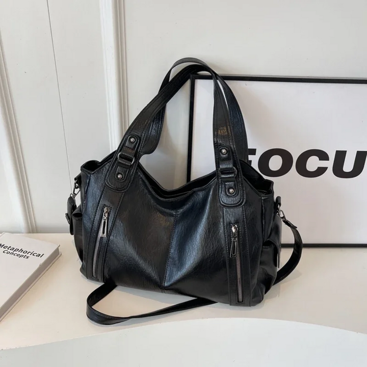 Detail of the hardware on a black vegan leather women's shoulder bag, polished finish