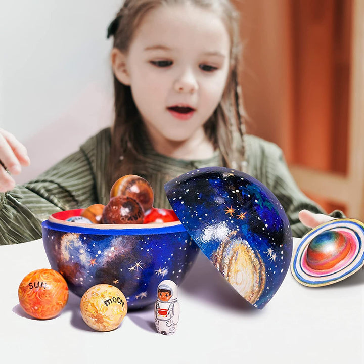 Child's hands arranging wooden planet models on a base, teaching solar system order & space learning.