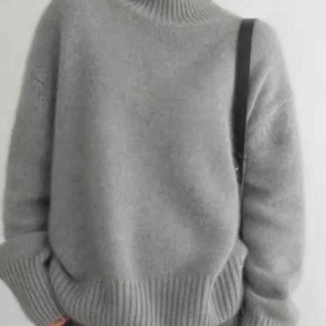 Full shot of women's beige oversized knit turtleneck sweater, emphasizing its relaxed silhouette.