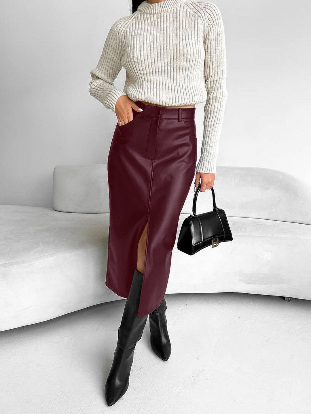 Close-up of a women's elegant black midi skirt with a delicate slit, highlighting its quality and design.