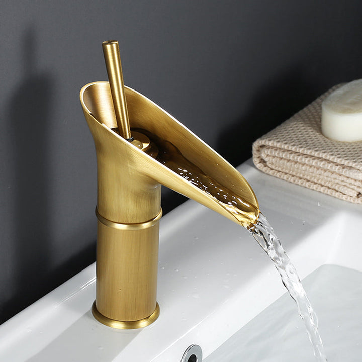 Antique brass waterfall basin tap. Elegant gold bathroom faucet for luxury home decor.