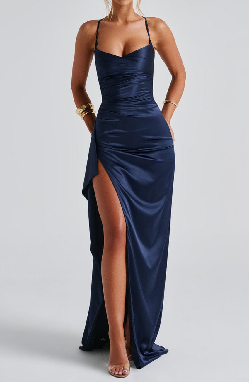 A woman modeling a flowing navy blue strappy high slit maxi dress.