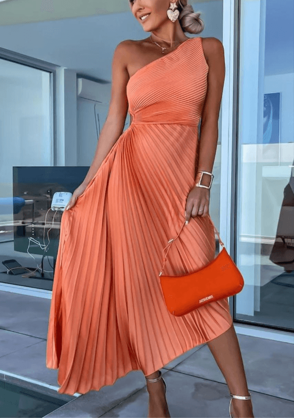 Elegant one shoulder pleated maxi dress in a soft coral fabric, perfect for a wedding guest