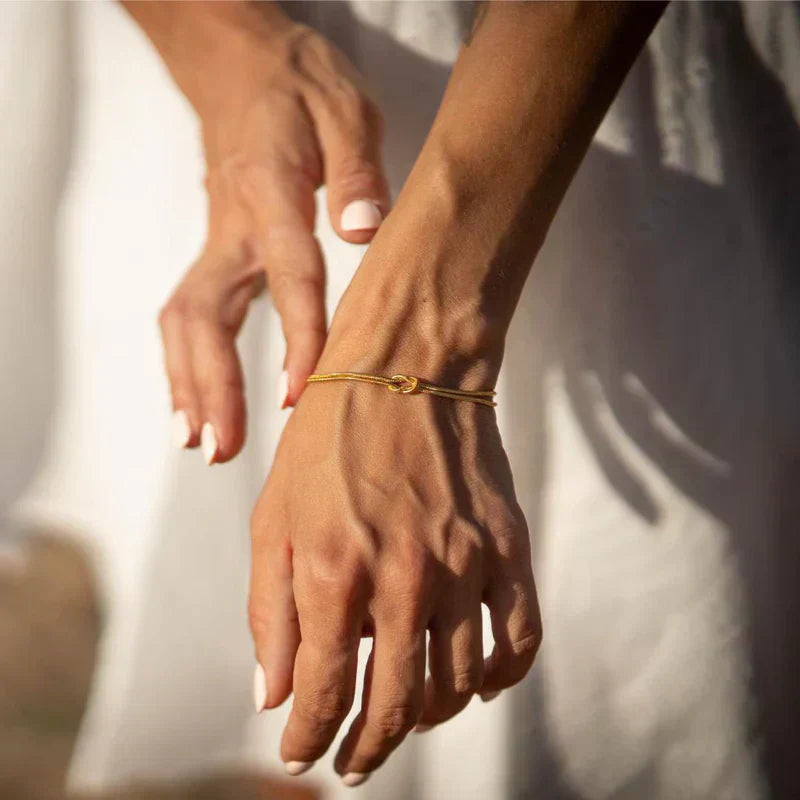 Refined knot detail on a delicate stainless steel women's bracelet, a stylish and subtle accessory.