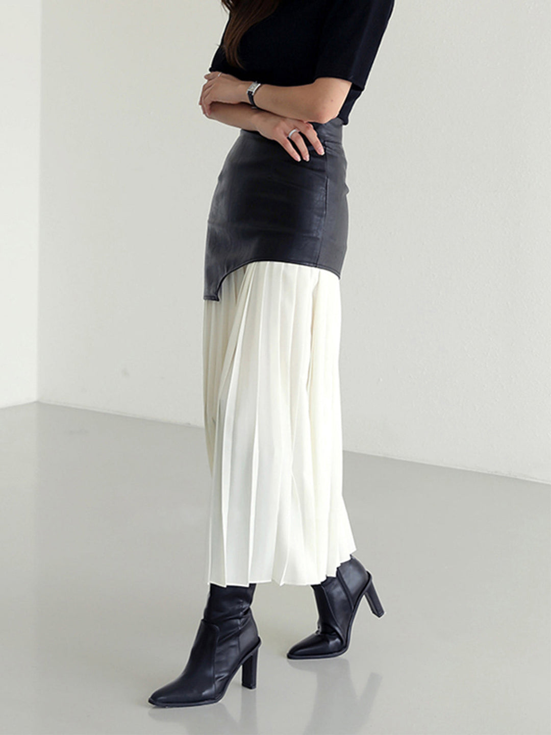 Close-up of the pleated detail on a women's asymmetrical midi skirt, showcasing quality craftsmanship.