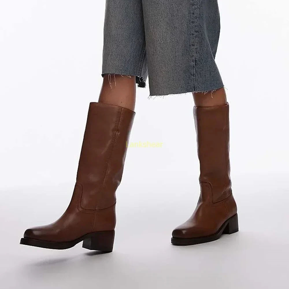 Fashionable women's knee-high leather boots featuring a high block heel, ideal for an elegant look.