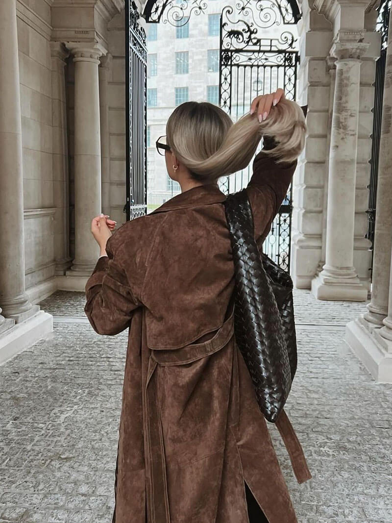 Close-up of the lapel collar and belted detail on a women's elegant brown trench coat
