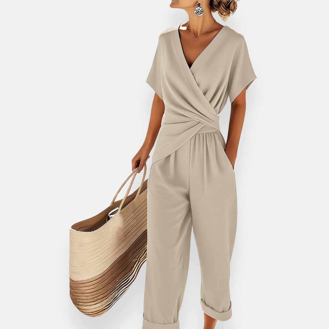 Full length view of a women's one-piece jumpsuit featuring draped fabric and bow accent