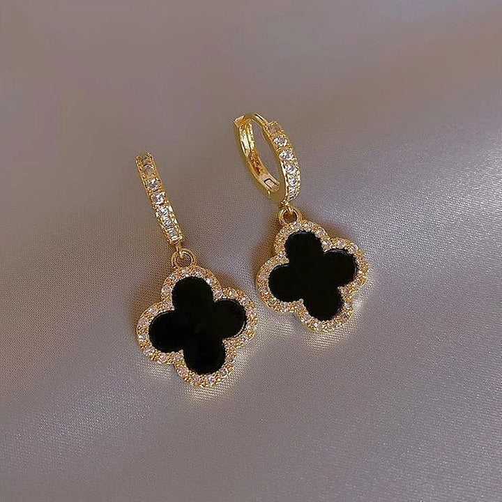 Close-up of elegant women's gold-plated lucky clover leaf earrings, showcasing crystal details & symbolic charm.