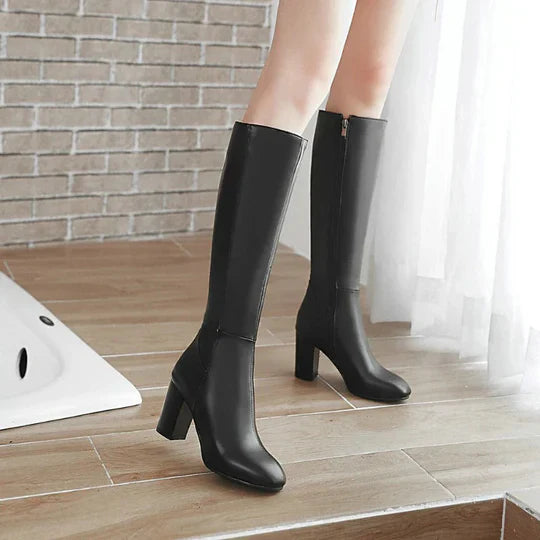 Fashionable women's knee-high heeled boots with a classic style, featuring a sleek design and side zipper.