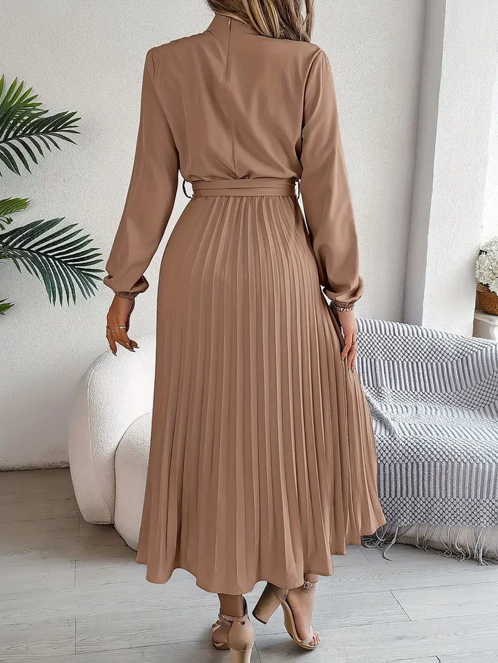 Women's long sleeve pleated maxi dress with a refined belted waist, a staple for modest fashion.