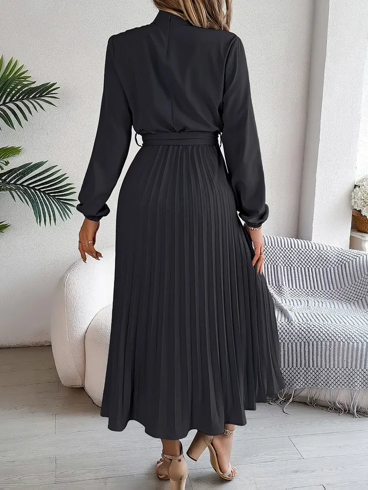 Front shot of a women's formal long sleeve pleated belted maxi dress, ready for an elegant event.