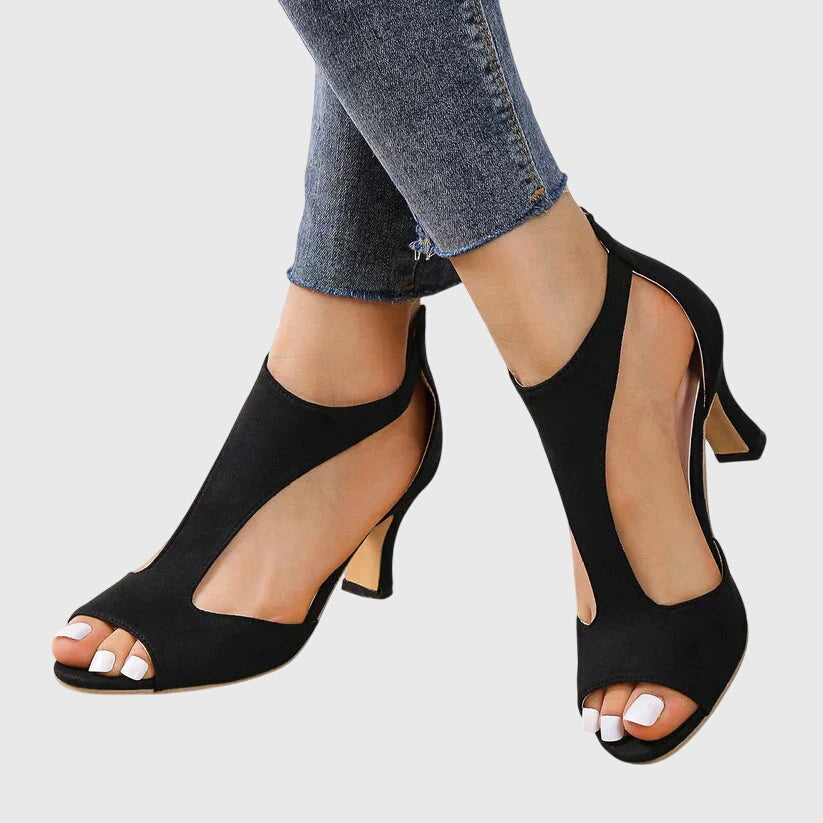 Pair of women's black strappy stiletto heels from a side angle, showcasing the high heel and cutout elegance.