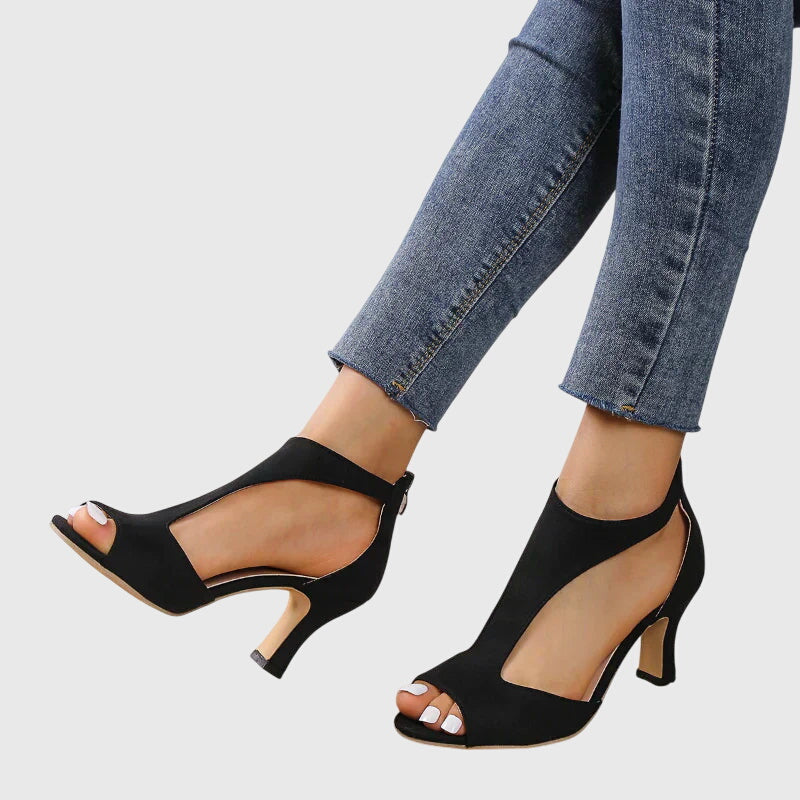 Detailed shot of the high stiletto heel and elegant cutout design on a women's black party shoe.