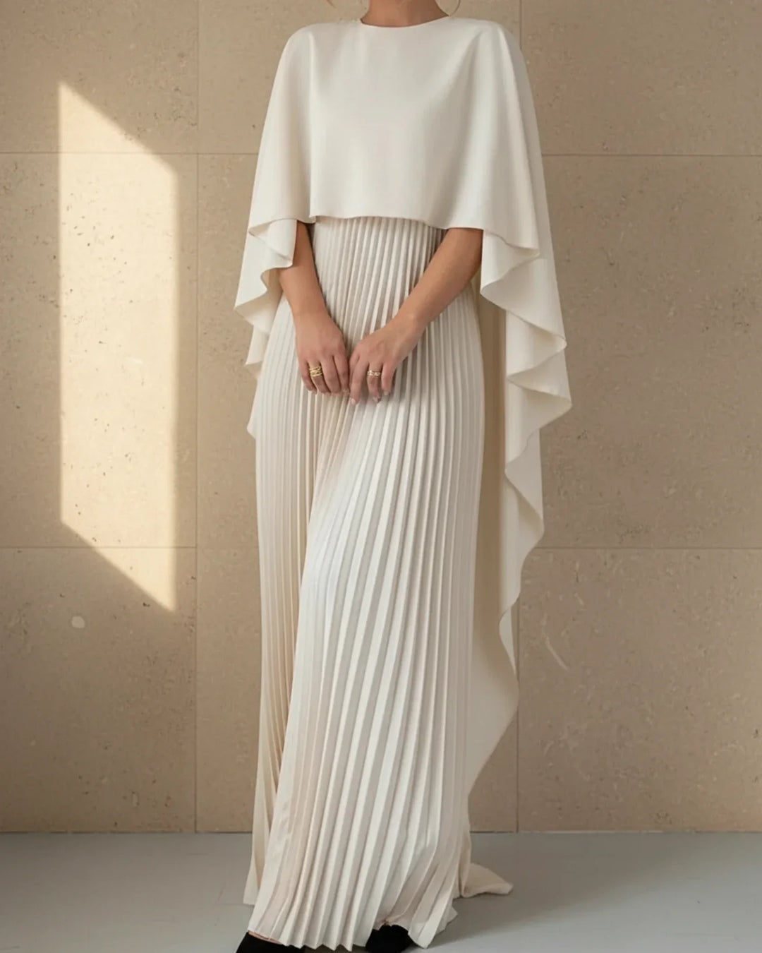 Chic women's wedding guest maxi dress with elegant pleats and a sophisticated cape. Ideal for special occasions.