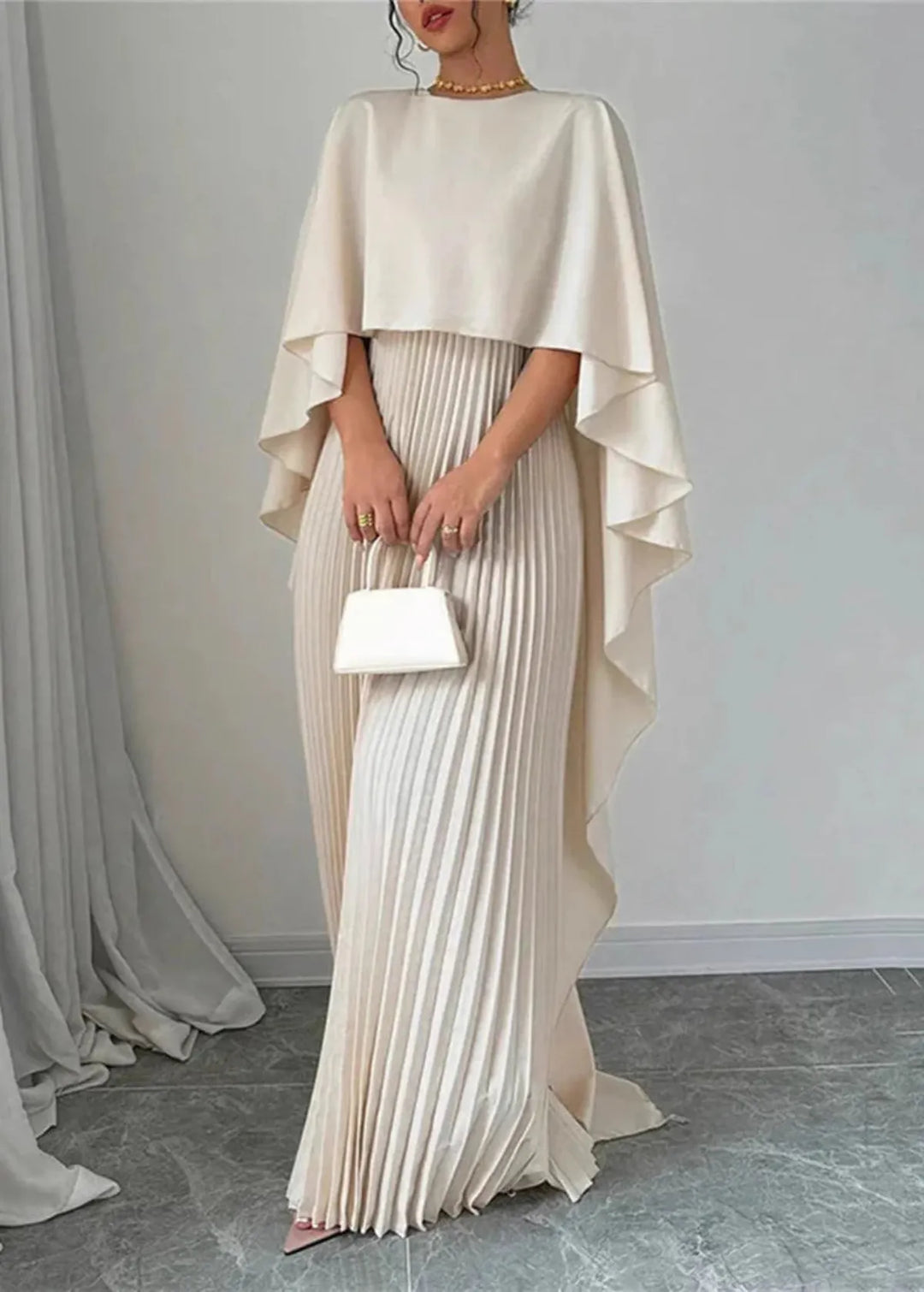 Stylish women's wedding guest pleated cape maxi dress with elegant flowing fabric, suitable for formal events.