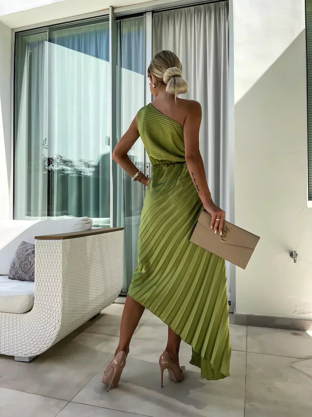 Full-length shot of a woman wearing a black pleated one shoulder midi dress, a chic party dress.