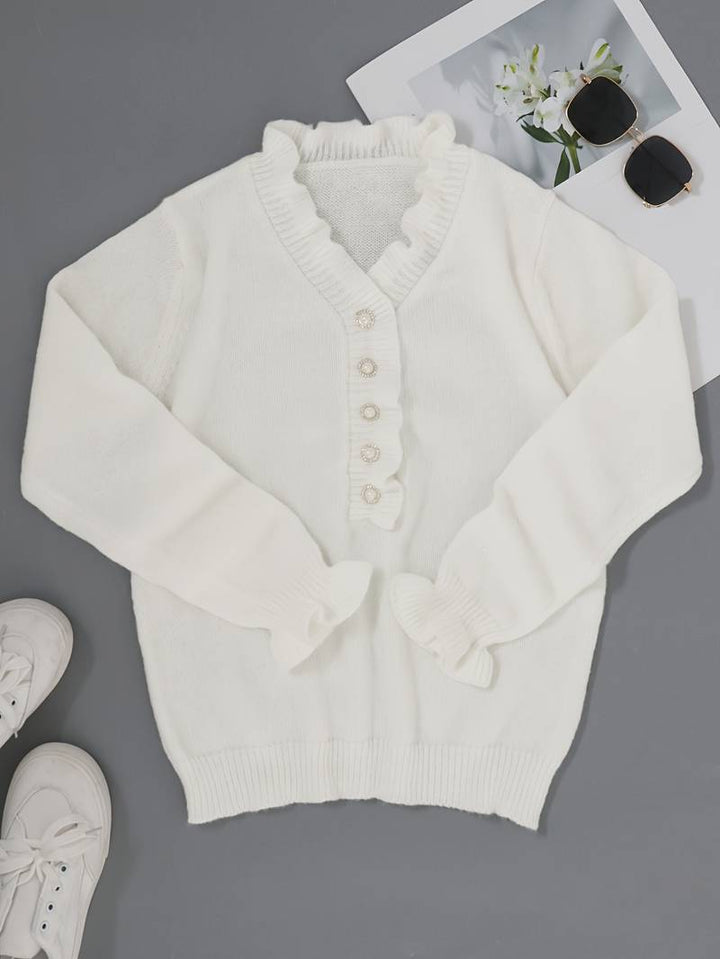 Close-up of a white women's ruffle blouse with delicate fabric and an array of shiny decorative buttons