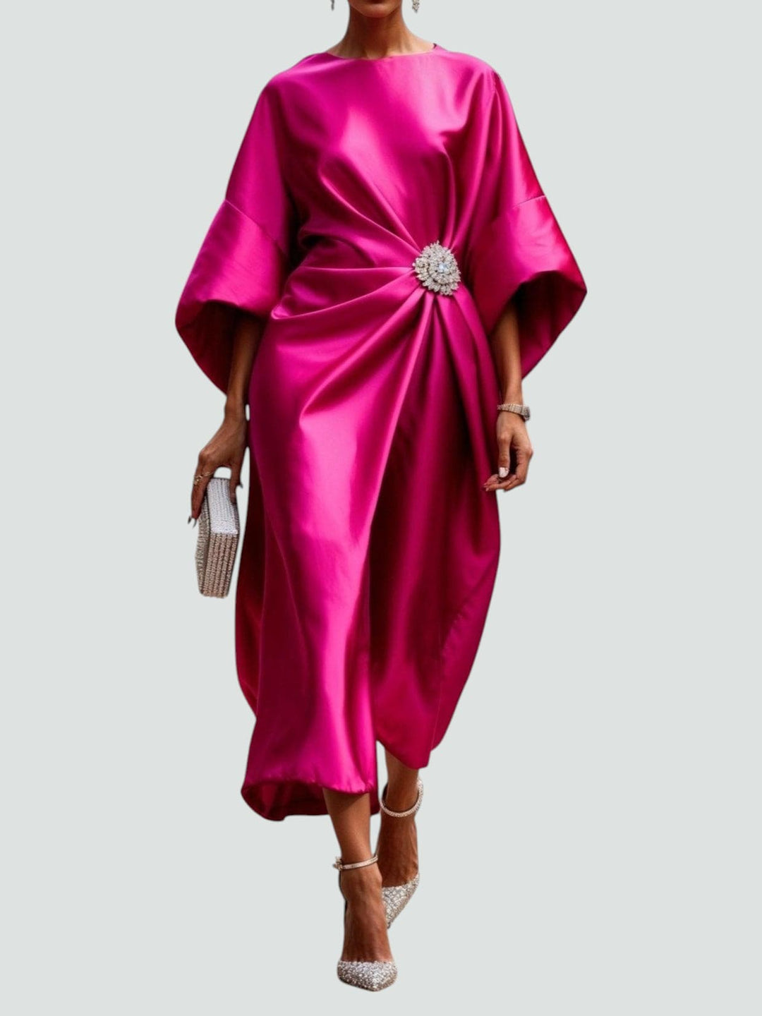 Close-up of the draped fit and brooch detail on a sophisticated women's satin midi dress.