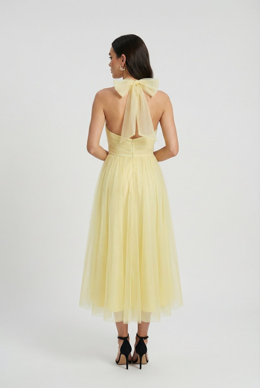 Flowing yellow halter neck midi dress for women, with a chic back tie detail, ideal for elegant summer events.