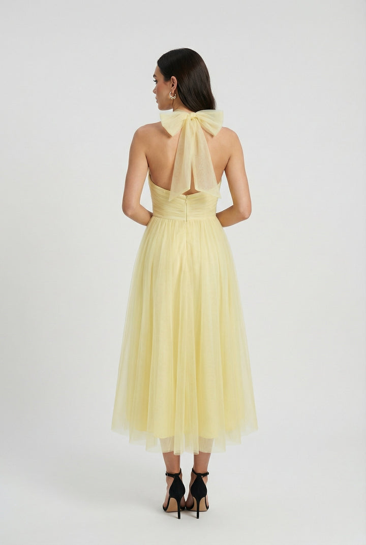 Flowing yellow halter neck midi dress for women, with a chic back tie detail, ideal for elegant summer events.