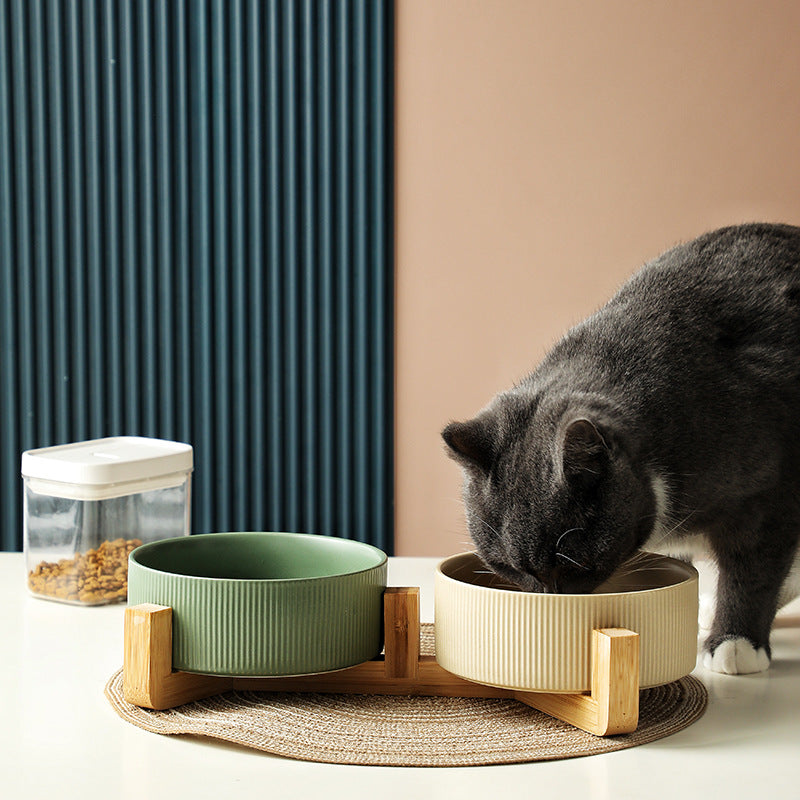 Modern elevated pet feeder with two white ceramic bowls and a natural wood stand.