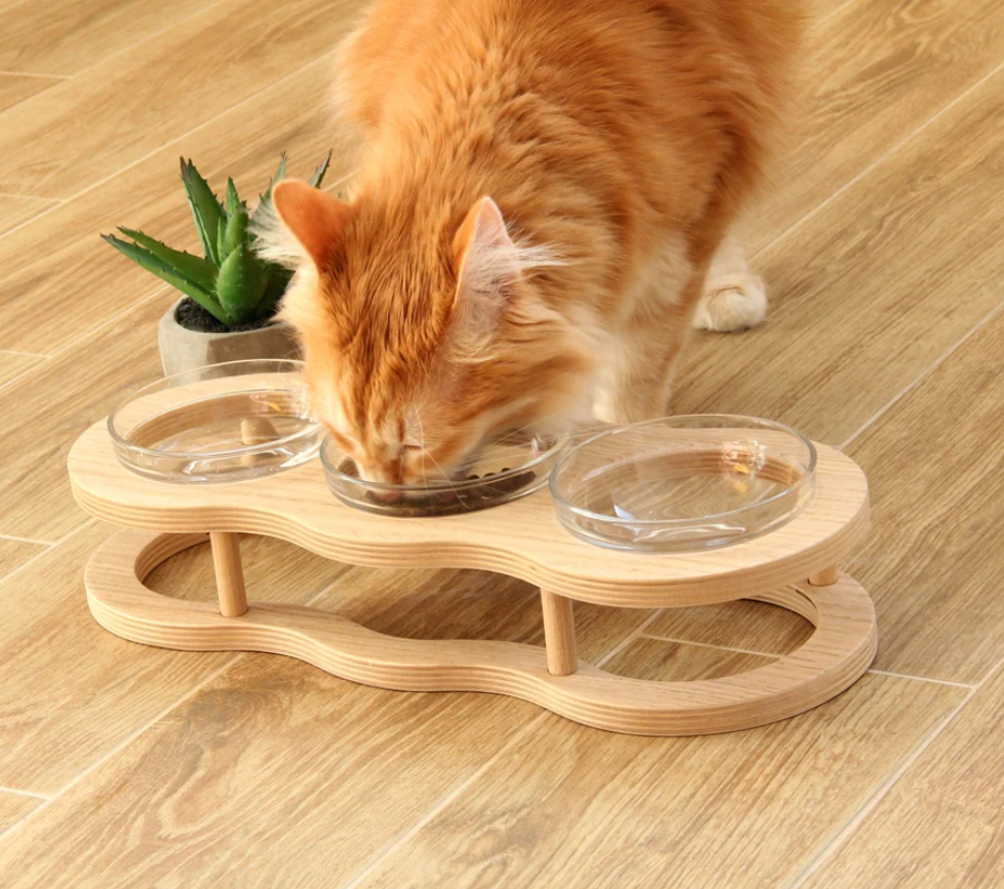 Elevated wooden pet feeder with two clear glass bowls & non-slip base for dogs & cats. Promotes healthy posture.