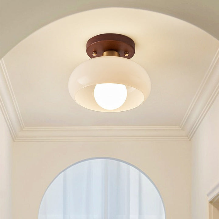 Elegant French Bauhaus ceiling lamp featuring warm wood and opal glass, providing atmospheric light for home decor.