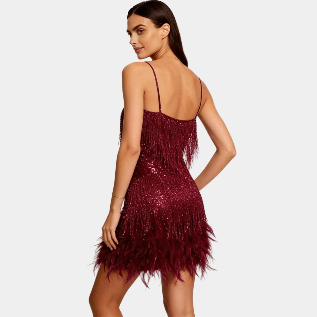 Back view of a women's spaghetti strap sequin dress with feather hem detail.