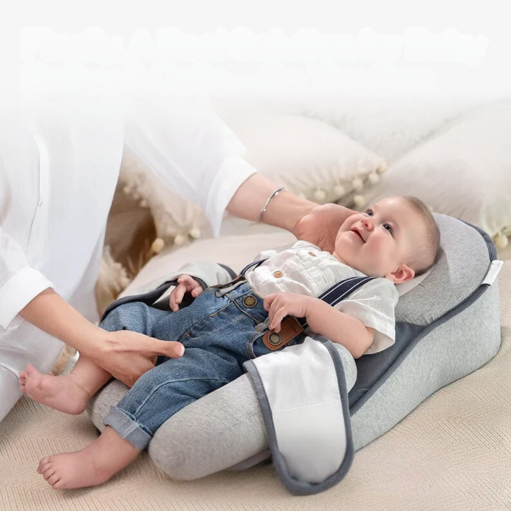 Grey infant anti-reflux pillow bed for safe newborn sleep, aiding digestion & colic relief. Portable baby support.