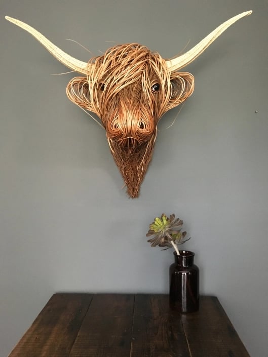 Natural rattan wall sculpture, rustic boho Toro art adding organic texture to interior spaces.