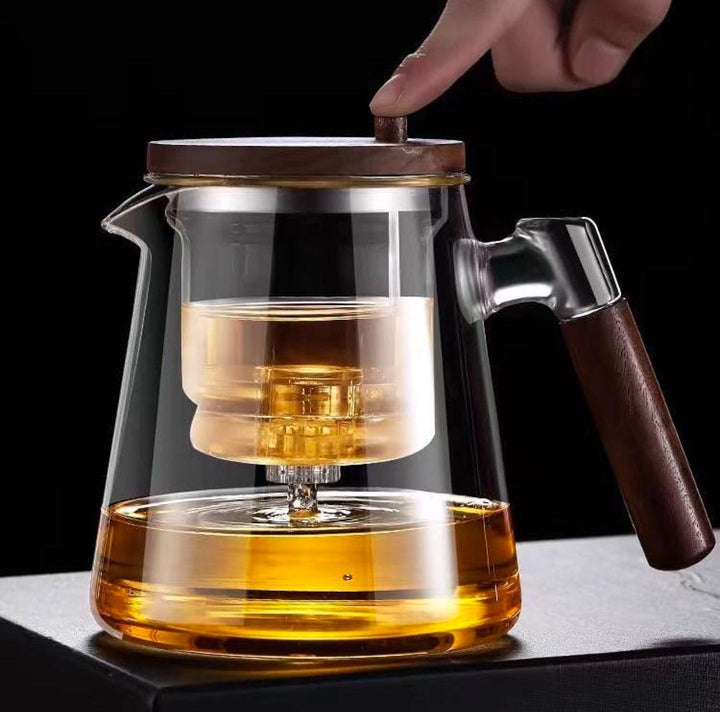 Heat-resistant borosilicate glass teapot with a built-in tea infuser for brewing loose leaf tea, featuring a stylish wooden handle.