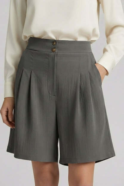 Detail of the high waist and pleats on chic khaki tailored shorts.