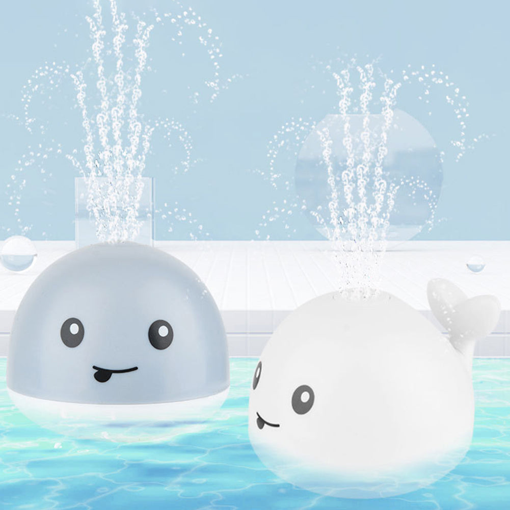 Toddler playing with an adorable whale bath sprinkler toy, featuring colorful LED lights for engaging fun bath time.