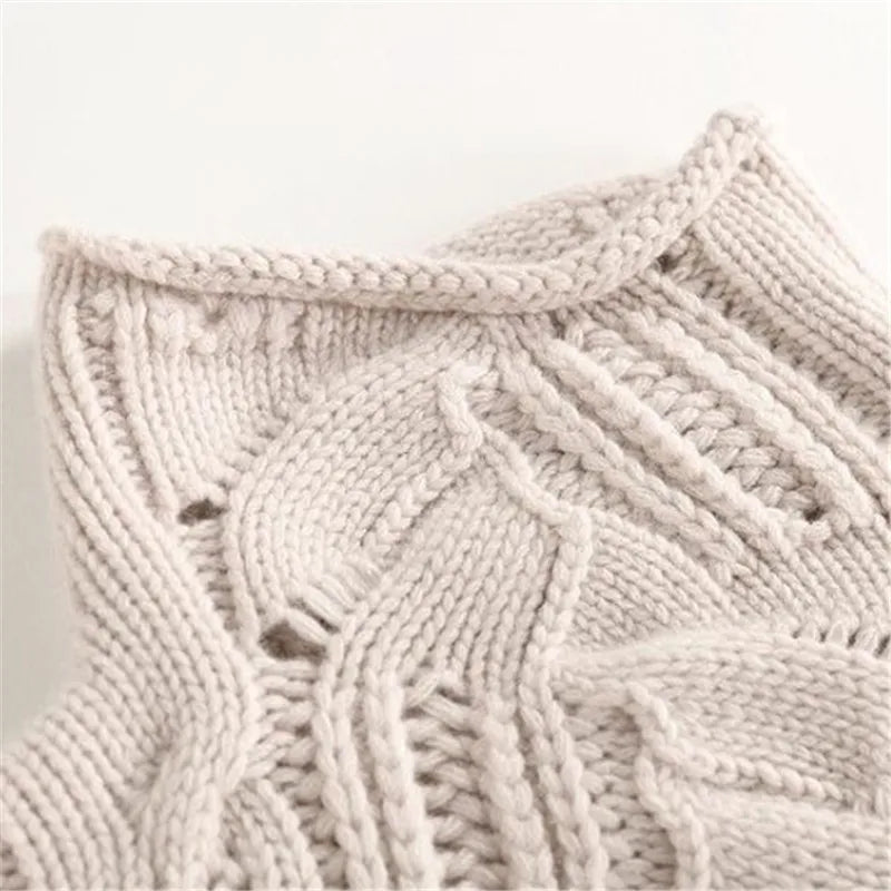 Close-up of a women's beige cable knit cashmere sweater, rich texture.
