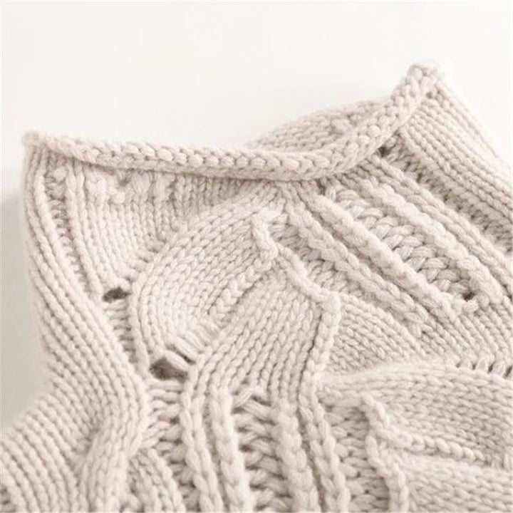 Close-up of a women's beige cable knit cashmere sweater, rich texture.