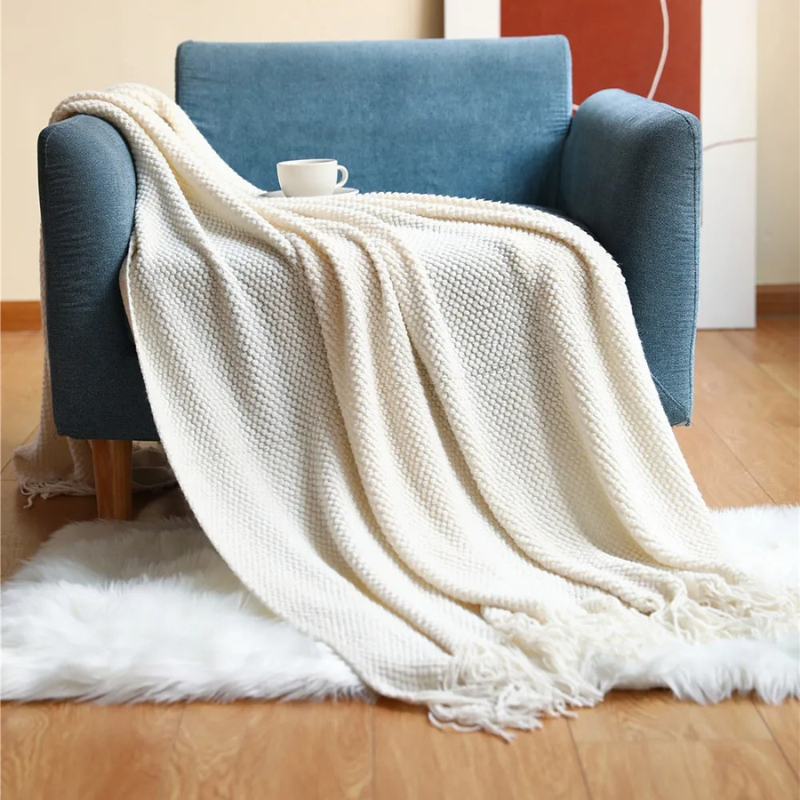 Cozy modern throw blanket with tassels, soft merino-style comfort for bedroom or lounge area.