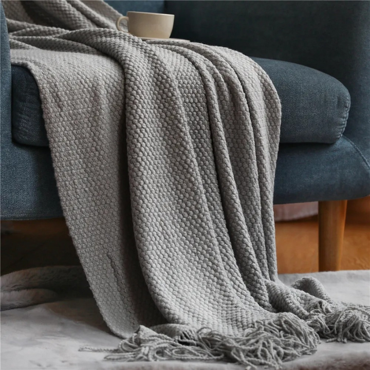 Cozy decorative throw blanket in merino-style with tassels, enhancing living room comfort.