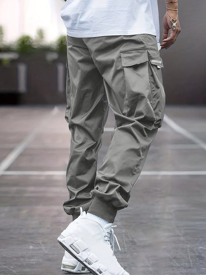 Khaki men's utility cargo jogger pants with multiple pockets and an adjustable drawstring for casual wear.