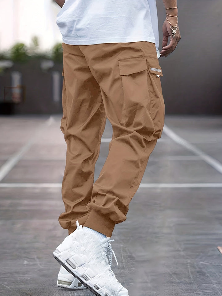 Beige men's cargo jogger pants with an elastic drawstring waist and spacious pockets, suitable for daily wear.