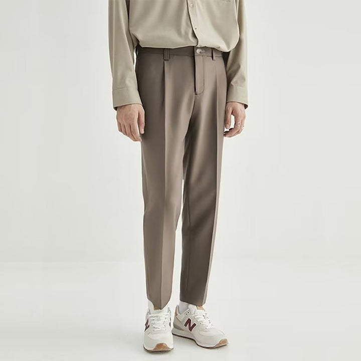 Light grey men's pleated cropped dress pants, high-waisted design for a sleek, modern aesthetic.